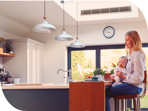 Frau sitzt mit Baby auf dem Schoß am Küchentisch